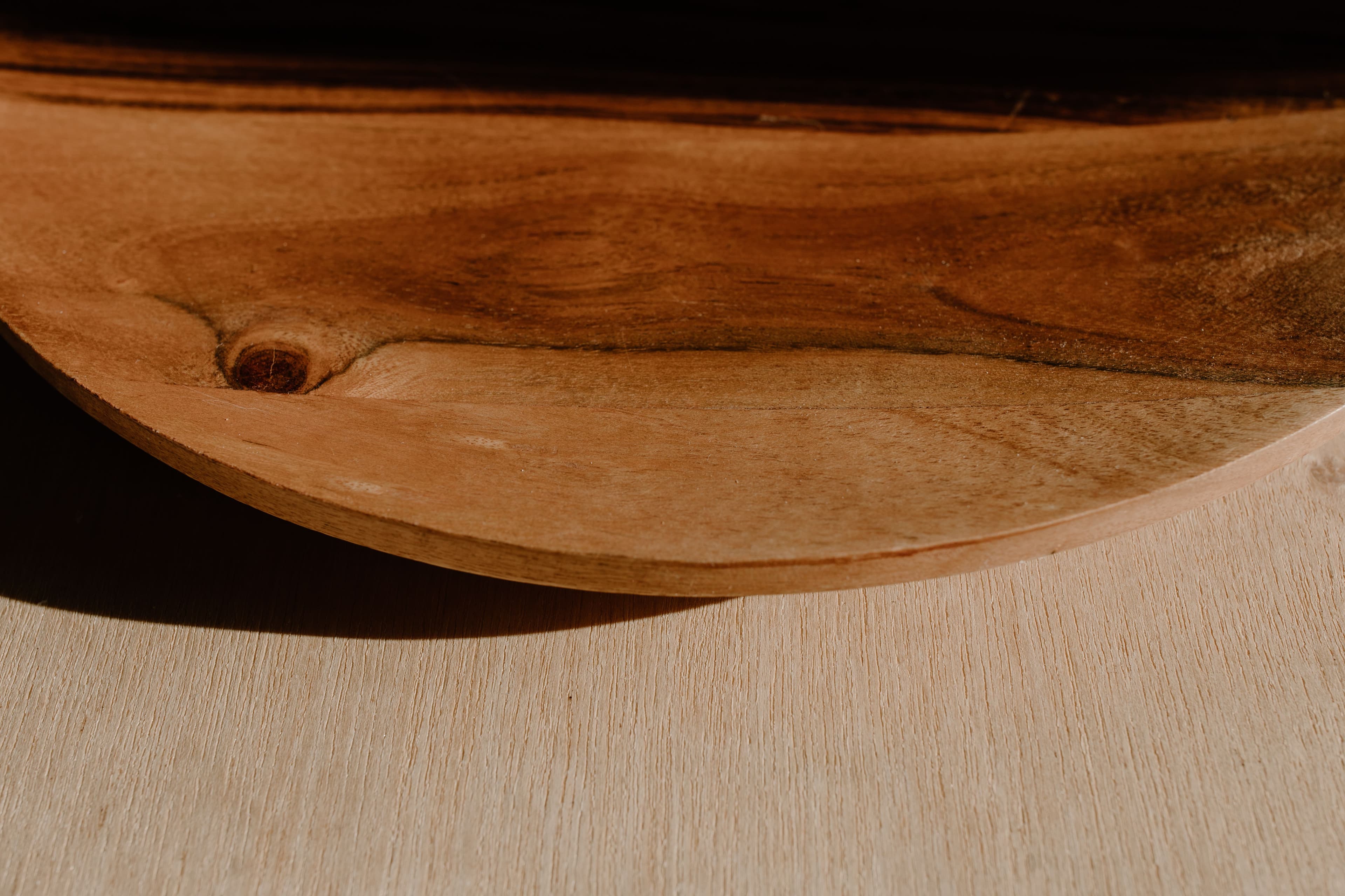Gros plan sur le bord d'un plat en bois sculpté à la main, baigné de lumière naturelle